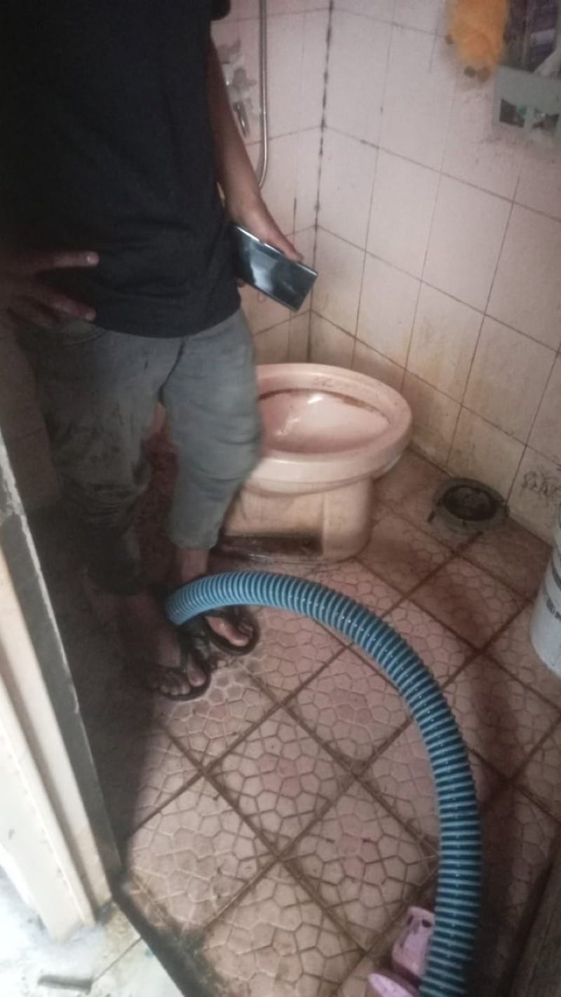Teknisi menangani kloset mampet menggunakan selang sedot bertekanan